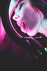 Wall Mural - Emotional studio portrait of a young woman in a wireless headphones with ring flash effect. Round LED Circle Lamp.