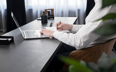 Poster - Businessman hands taking notes in notebook and surfing information on Internet or preparing for corporate event or studying distantly. Online work and education concept. High quality photo