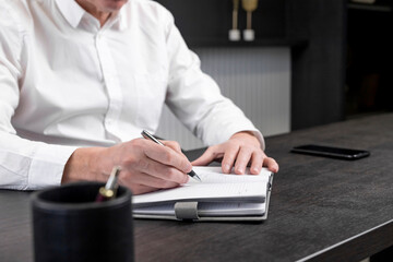 Poster - Businessman hands taking notes or writing agenda in planner at office workplace. Business planning and strategy concept. High quality photo