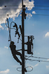 The silhouette of power lineman replacing a transformer and hotline clamp, bail  clamp. Using clamp stick grip all type, wearing personal protective equipmen,