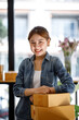 © David - Startup SME small business entrepreneur SME or freelance Asian woman using a laptop with box, Young success Asian woman with her hand lift up, online marketing packaging box and delivery, SME concept.