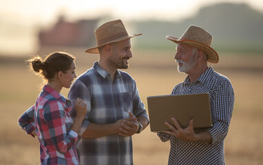 Sticker - Three farmers with laptop talking in field during harvest