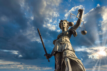 Wall Mural - Justitia monument in Frankfurt roemerberg during sunset with cloudy sky, low angle