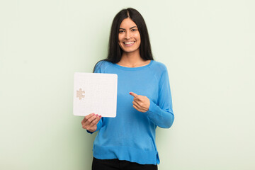 Wall Mural - young pretty hispanic woman smiling cheerfully, feeling happy and pointing to the side. puzzle concept