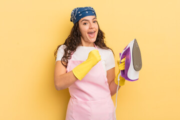 Wall Mural - young pretty hispanic woman feeling happy and facing a challenge or celebrating. iron and clothes concept