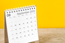 September 2022 Desk Calendar On Wooden Table With Yellow Background.