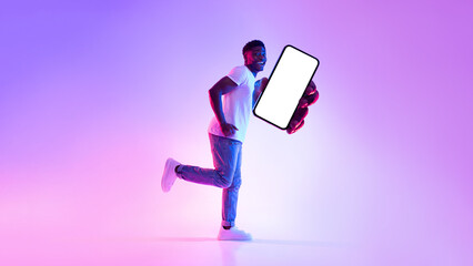 Poster - Smartphone screen mockup. Positive young black man running with blank cellphone, recommending new app in neon light
