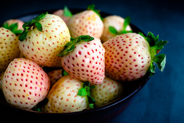 Wall Mural - Freshly Washed Pineberries in a Wooden Bowl: Closeup view of wet white strawberries in a dark wood bowl