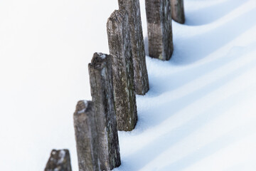 An old wooden fence sunk in the snow. A heavy snowfall brought down a wooden fence.