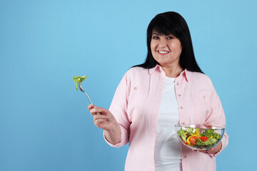 Sticker - Beautiful overweight woman eating salad on light blue background, space for text. Healthy diet