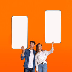 Young couple showing blank empty smartphone screens for mockup