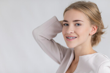 Young caucasian girl holding a present wearing Christmas sweater on white background holding an invisible braces aligner and rising thumb up, recommending this new treatment. Dental healthcare concept