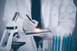 © Bussarin - biochemical research scientist working with a microscope for the virus,Doctor man write a history of the experimental results in a notebook, laboratory glassware containing chemical liquid for design.