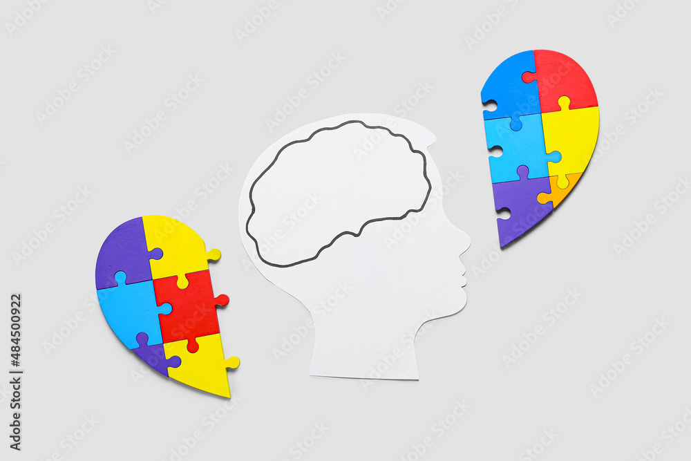 Paper human head with colorful puzzle pieces on light background. Concept of autistic disorder