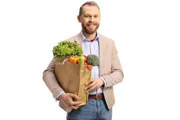 Poster - Young man holding a paper bag with vegetables and smiling