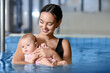 Young woman with her little baby in swimming pool