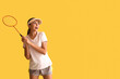 © Pixel-Shot - Happy female badminton player on yellow background