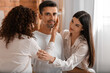 © Pixel-Shot - Man with two beautiful women in bedroom. Polyamory concept