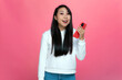 © Georgii - Excited young asian girl hold phone shocked by incredible message about discounts in online store app on pink background