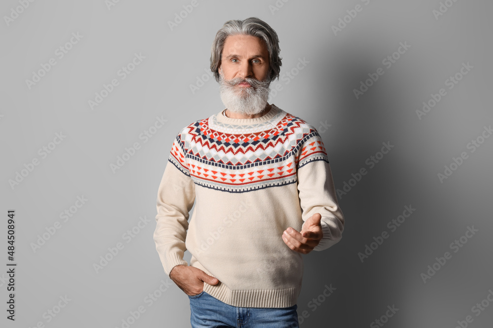 Handsome senior man in knitted sweater on grey background