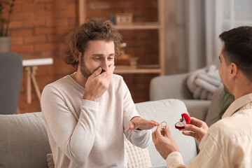 Sticker - Young gay putting engagement ring on his boyfriend's finger at home