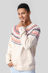 Wall Mural - Handsome African-American guy in knitted sweater on light background