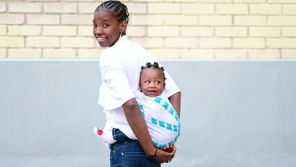 an african mother with a baby on her back looking back