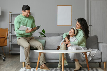 Sticker - Happy young man reading book to his wife and little daughter at home