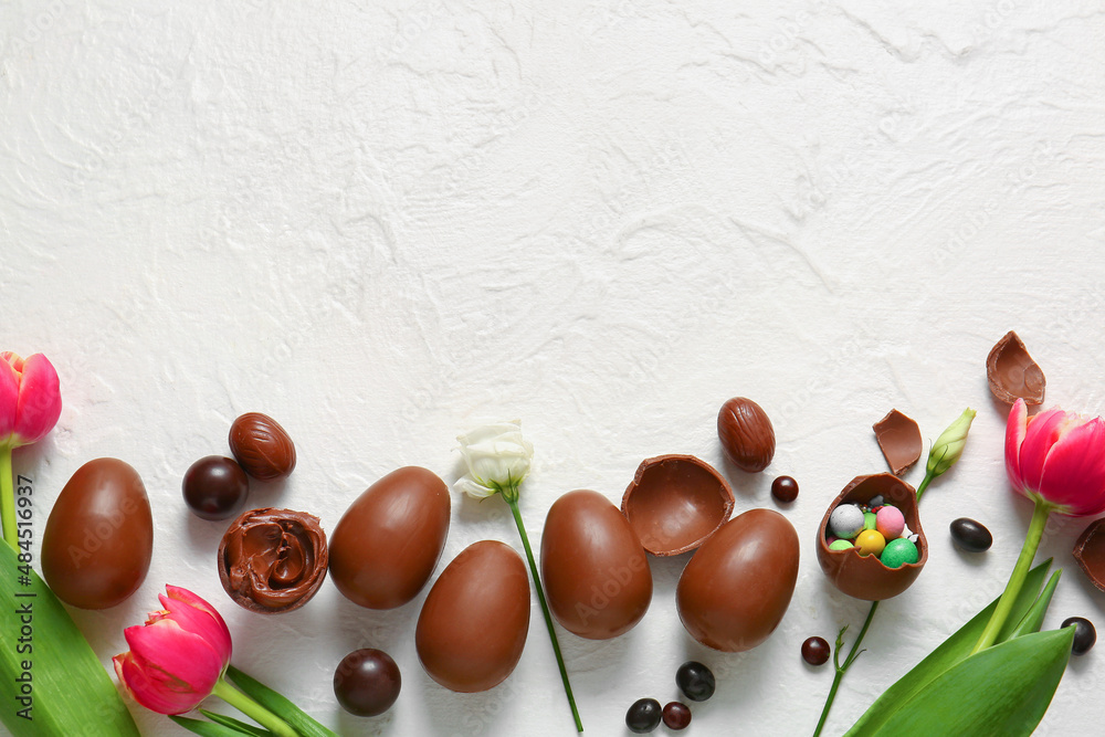 Composition with chocolate Easter eggs and flowers on light background