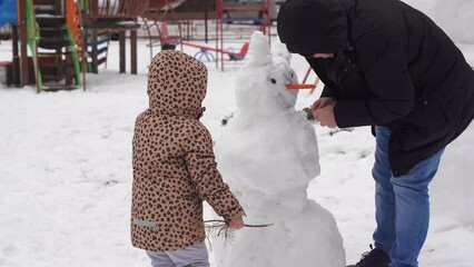 Wall Mural - Father and child playing on winter snowy day. Creating snowman with family on the urban backyard.