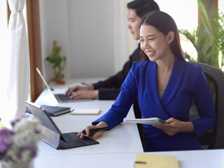 Happy businesswoman using portable tablet at her office desk.