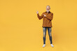 Full size body length fun elderly gray-haired bearded man 40s years old wears brown shirt point fingers aside on workspace area copy space mock up isolated on plain yellow background studio portrait.