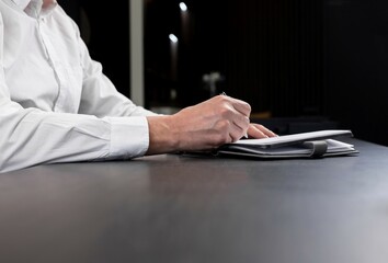 Poster - Businessman opened planner and is taking work notes or writing agenda. Man hands closeup. . High quality photo