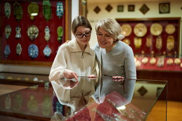 mother and daughter looking at expositions of previous centuries in museum