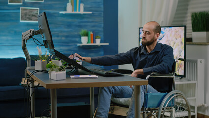 Poster - Disabled photographer editing pictures in photography studio. Man with handicap working as editor and retouching photos with graphic tablet and software while sitting in wheelchair.