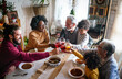 © NDABCREATIVITY - Happy multiethnic multigeneration family having fun together around kitchen table.