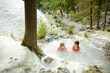 © MNStudio - Young girls bathing in Bagni San Filippo, small hot spring containing calcium carbonate deposits, forming white concretions and waterfalls. Geothermal pools and hot springs in Tuscany, Italy.
