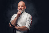 Fototapeta  - Professional elderly chef dressed in uniform against dark background