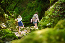 Young Girls Hiking In Botro Ai Buchi Del Diavolo, Rocky Gorge Hiking Trail, Leading Along Dried Up River. Footpath Extending Into The Woods Near San Gimignano Town, Tuscany, Italy.