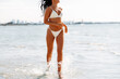 © Syda Productions - people, summer and swimwear concept - happy young woman in bikini swimsuit running in water beach