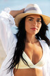 © Syda Productions - people, summer and leisure concept - portrait of young woman in bikini swimsuit, white shirt and straw hat on beach