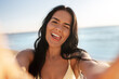 © Syda Productions - people, summer and swimwear concept - happy smiling young woman in bikini swimsuit taking selfie on beach