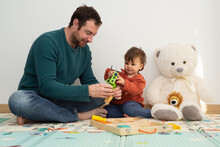 Young Father And His Little Girl Sitting On A Play Mat And Playing Together With Toy Tools. 