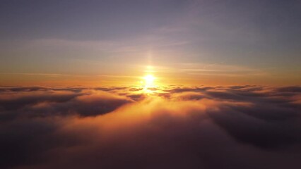 Wall Mural - Cinematic drone video of flying above the clouds. Fast clouds melting beneath, stunning sunset on the background