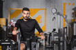 © LIGHTFIELD STUDIOS - Muslim sportsman looking at camera while training on elliptical trainer.