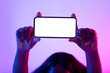 Unrecognizable young African American woman holding empty smartphone with mockup over her head in neon light, closeup