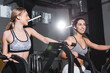 © LIGHTFIELD STUDIOS - Cheerful interracial women training on elliptical trainers in sports center.