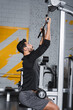© LIGHTFIELD STUDIOS - Side view of arabian sportsman training with lat pulldown machine in gym.