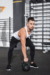 Wall Mural - Sportsman holding kettlebell in sports center.