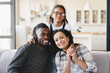 © InsideCreativeHouse - Happy smiling portrait of african-american family of three, parents and preteen daughter hugging embracing together relaxing on the couch at home. Homeowners, mortgage loan, real estate